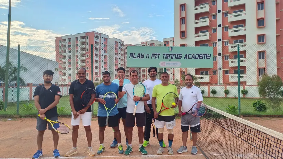 Adult players with racquets on court in front of the PLAY n FIT sign